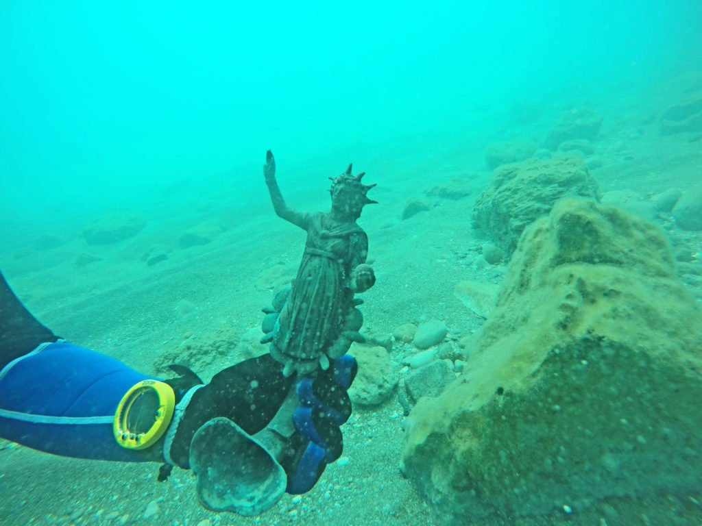 שבר נר ברונזה מעוטר בדמות האל סול כפי שנתגלה בים. צילום: רן פיינשטיין
