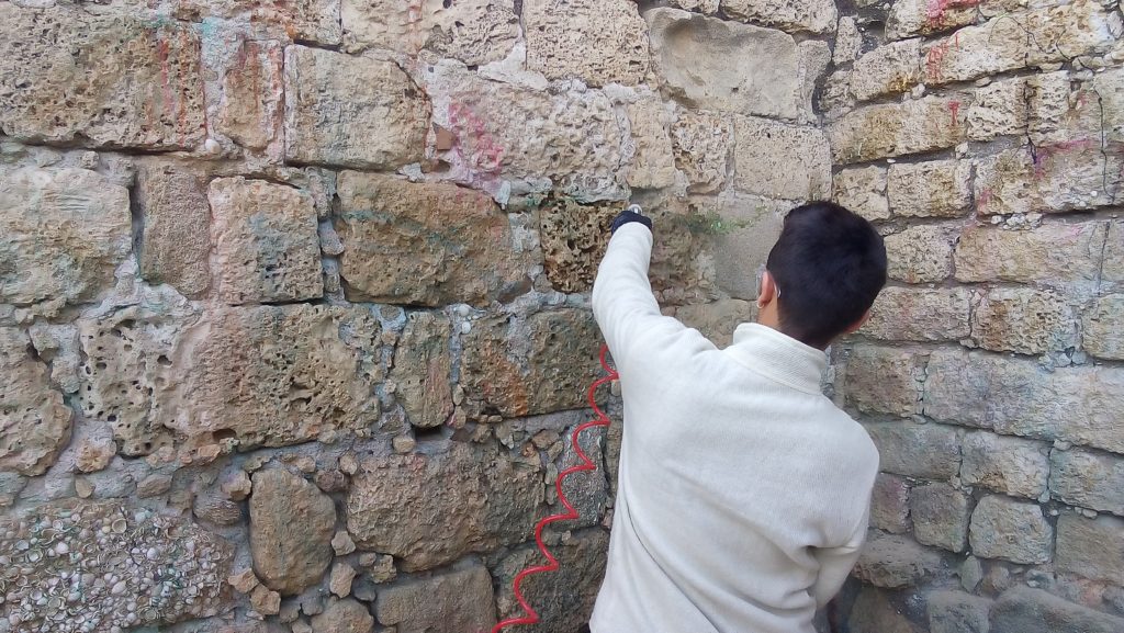 משמר של רשות העתיקות מנקה את קיר המצודה. צילום: אריאל ענבר