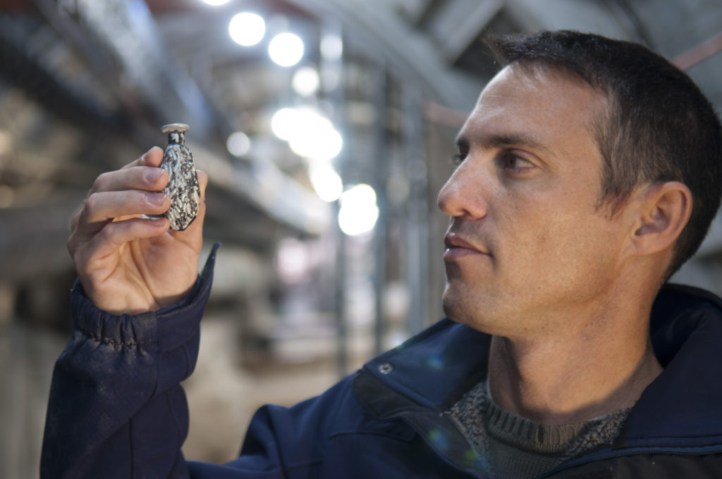 נחשון זנטון מחזיק כלי זכוכית קטן ונדיר בצורת תמר שנחשף בחפירות הרחוב. צילום: שי הלוי