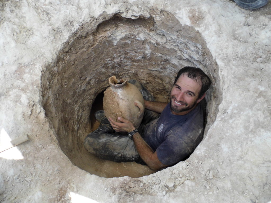 ארכיאולוג רשות העתיקות דוד תנעמי משתחל לפתח הקבר הצר ומוציא החוצה קנקן. צילום: שועה קיסילביץ