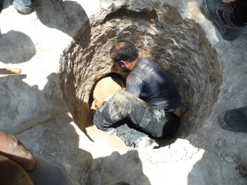 ארכיאולוג רשות העתיקות דוד תנעמי משתחל לפתח הקבר הצרומוציא החוצה קנקן. צילום: שועה קיסילביץ