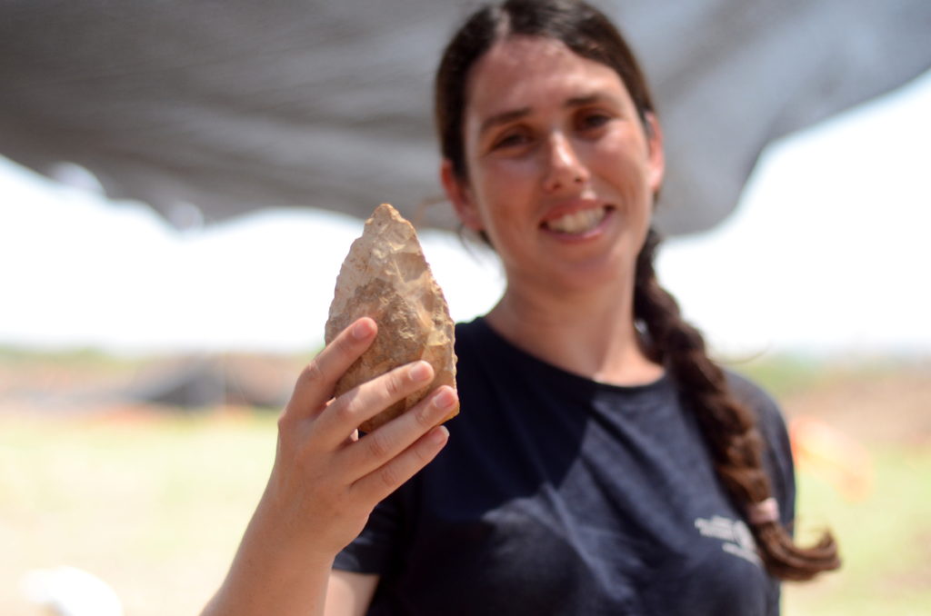 מעין שמר, מנהלת החפירה מטעם רשות העתיקות, מציגה אבן יד בת חצי מליון שנה
