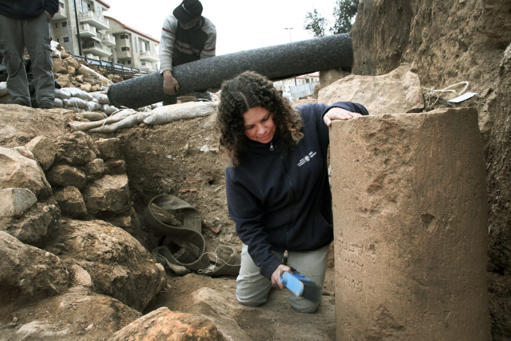 דנית לוי, מנהלת החפירה מטעם רשות העתיקות, ליד הכתובת כפי שנמצאה בשטח. צילום: יוֹלי שוורץ