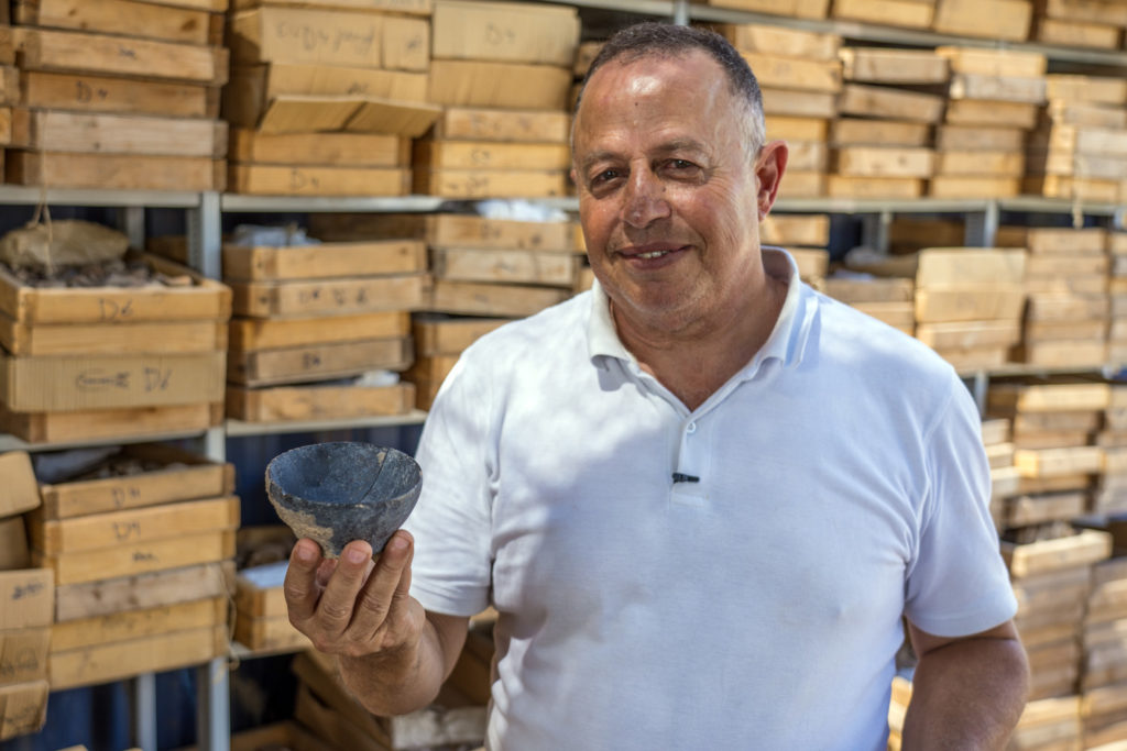 ד"ר חמודי חלאילה, מנהל החפירה מטעם רשות העתיקות, מחזיק קערית מהתקופה הניאוליתית. צילום: יניב ברמן