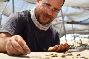 שחר קריספין, מומחה מטבעות ברשות העתיקות, סופר את מטבעות הזהב שנחשפו. צילום: יולי שוורץ