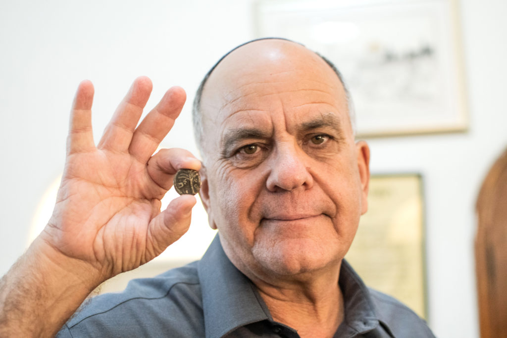 מנהל רשות העתיקות אלי אסקוזידו עם המטבע שיטוס לחלל. צילום יולי שוורץ