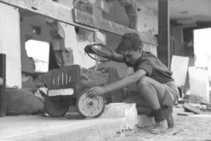 ילד משחק במכונית צעצוע הרוסה לאחר שביתו בקיבוץ נגבה הופגז על ידי הצבא המצרי - צילום: מנדלסון הוגו - ארכיון לע"מ