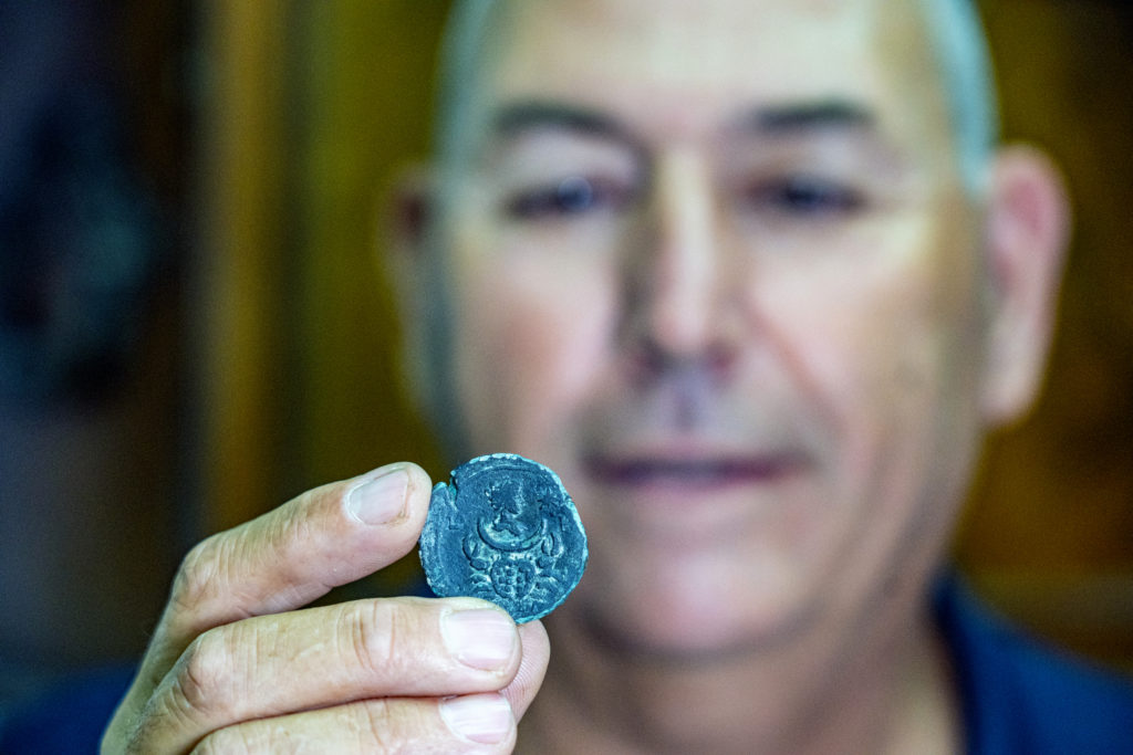 קובי שרביט, מנהל היחידה הימית של רשות העתיקות, עם המטבע שנמצא בסקר בימי. צילום: יניב ברמן