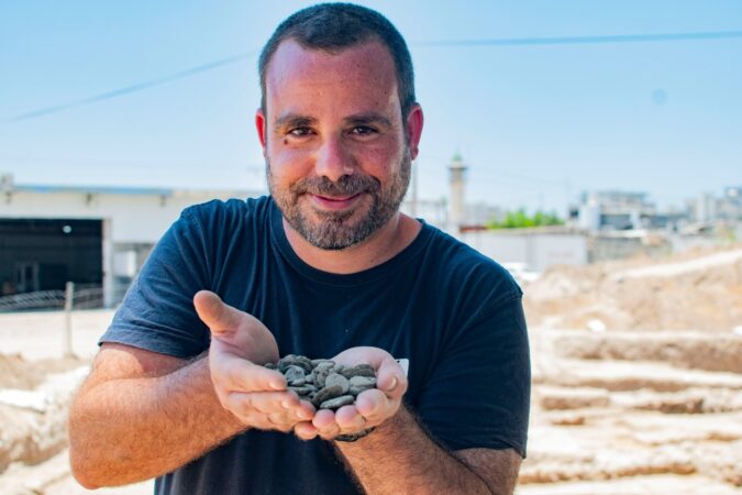 הארכיאולוג שחר קריספין מחזיק את מטמון המטבעות לאחר מציאתו. צילום יולי שוורץ