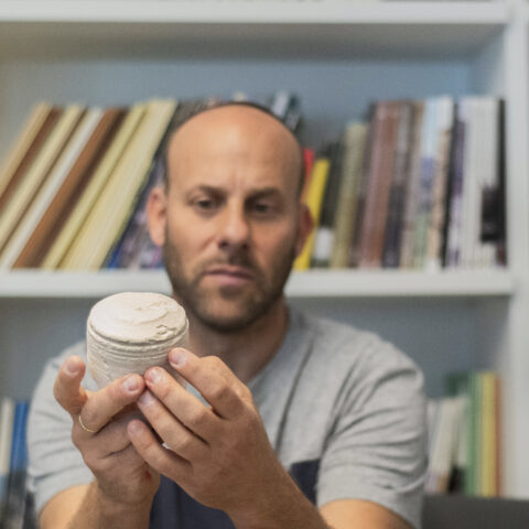 ד"ר איתן קליין מחזיק גרעין של כלי אבן בן כ-2,000 שנה. צילום: יולי שוורץ